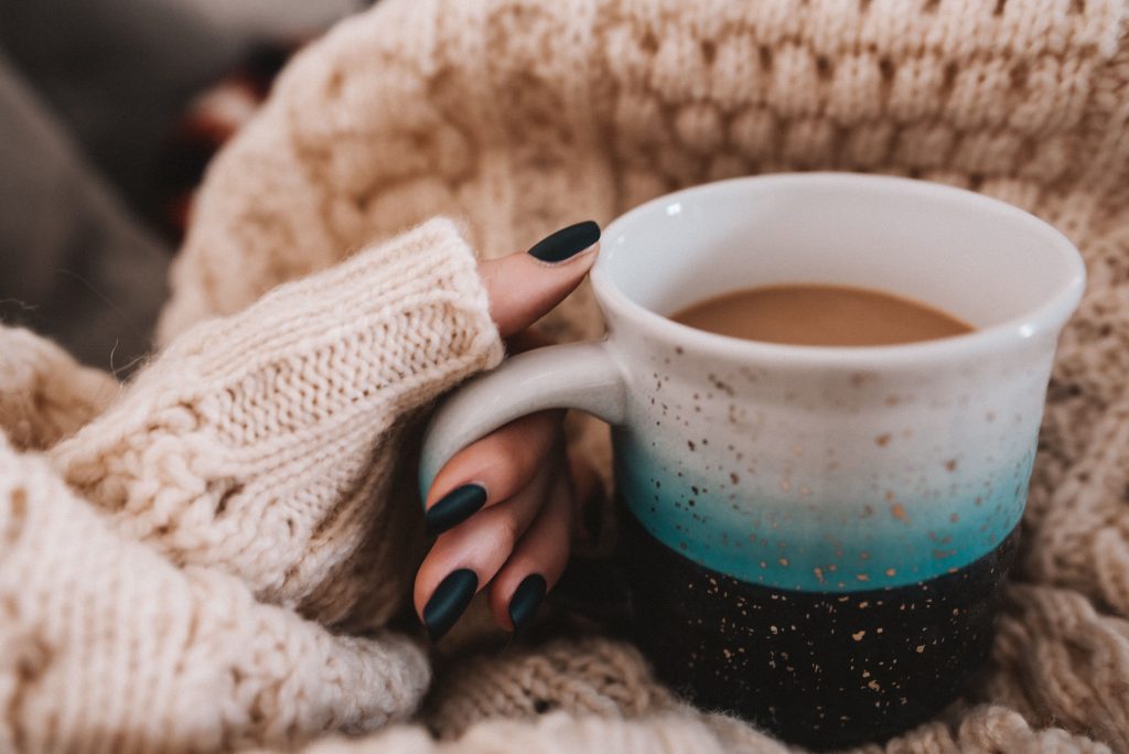 Drinking a hot tea with a cozy knitted jumper