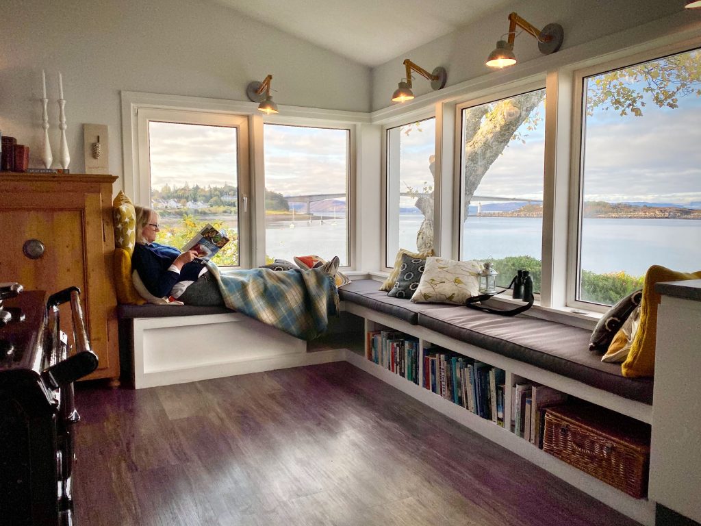 Woman reading in a cozy reading room overlooking the sea